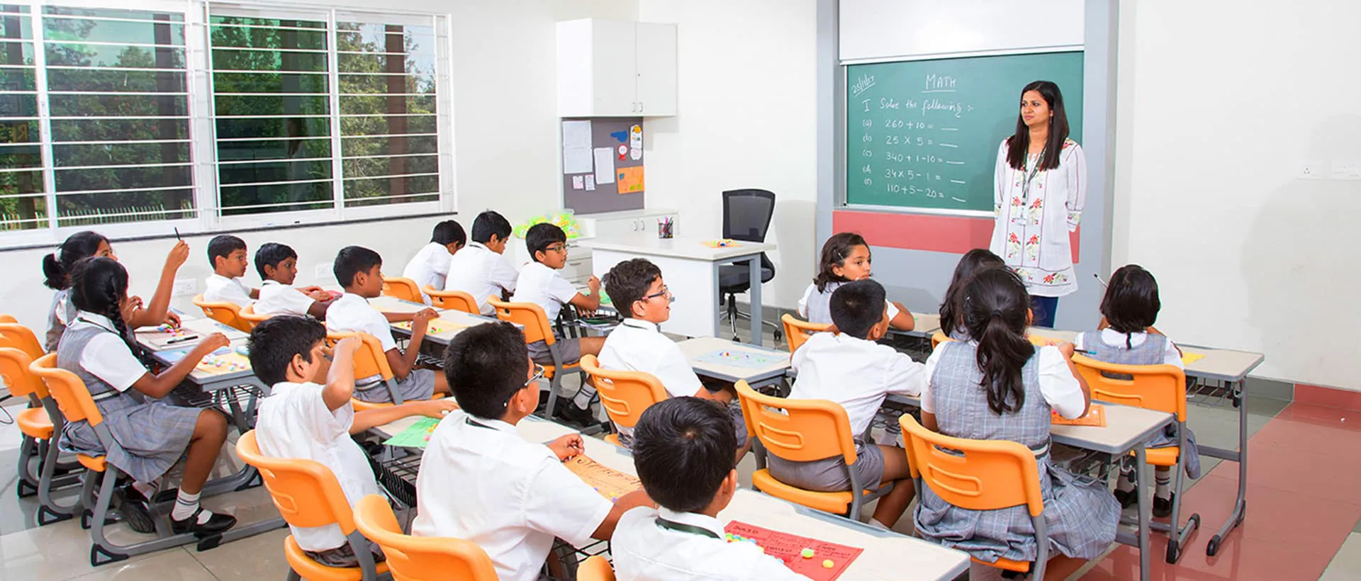 Greenwood High Bannerghatta math classroom with students in white uniforms learning from teacher at blackboard
